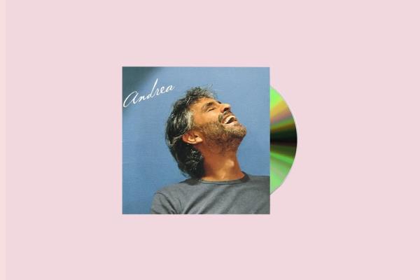 Andrea Bocelli with his eyes closed holding a CD